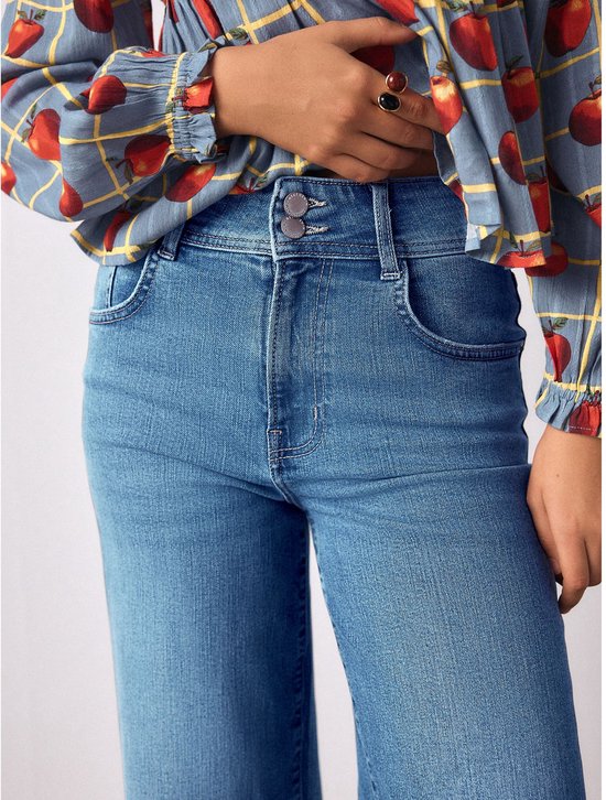 Close-up van de hoge taille van een lichtblauwe jeans met wijde pijpen en twee knopen.