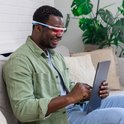 Man met AYO bril gebruikt rode lichttherapie tijdens tabletgebruik.