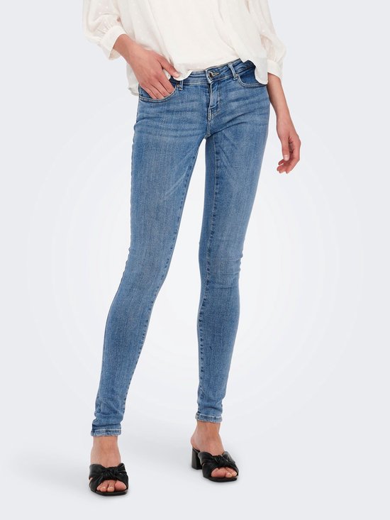 Bovenlichaam van een vrouw met lang blond haar, draagt een witte blouse en lichtblauwe skinny jeans.