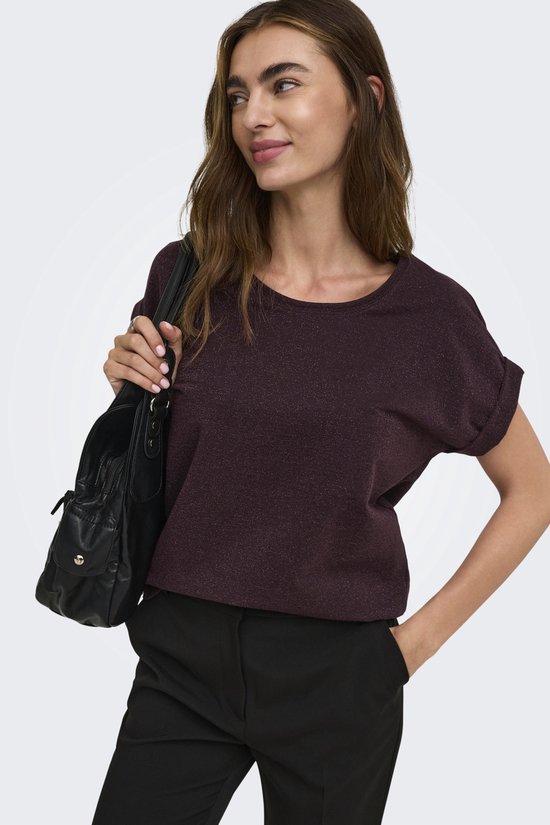 Model draagt donkerpaarse top met korte mouwen en glitterdetails.