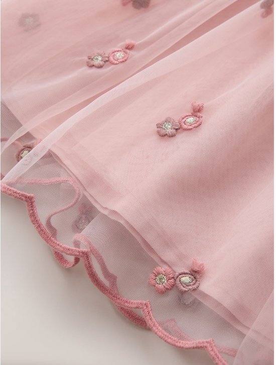 Close-up van de roze tule rok met bloemenborduursel en golvende zoom.