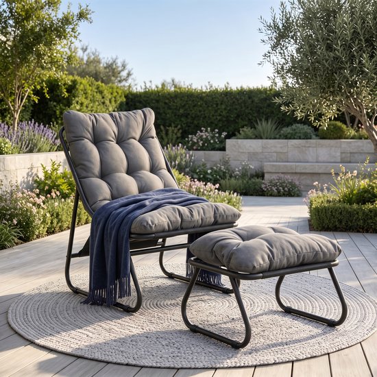 Fauteuil de salon gris avec repose-pieds et jeté bleu sur une terrasse.