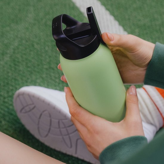 Vrouw houdt een mintgroene drinkbeker vast.