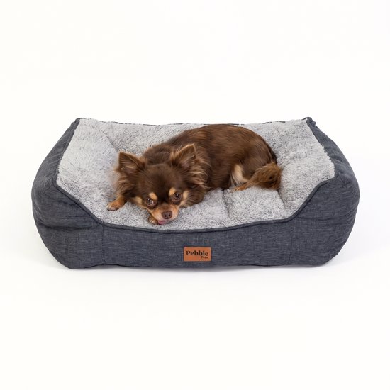 Chihuahua brun allongé sur un panier orthopédique gris doux.