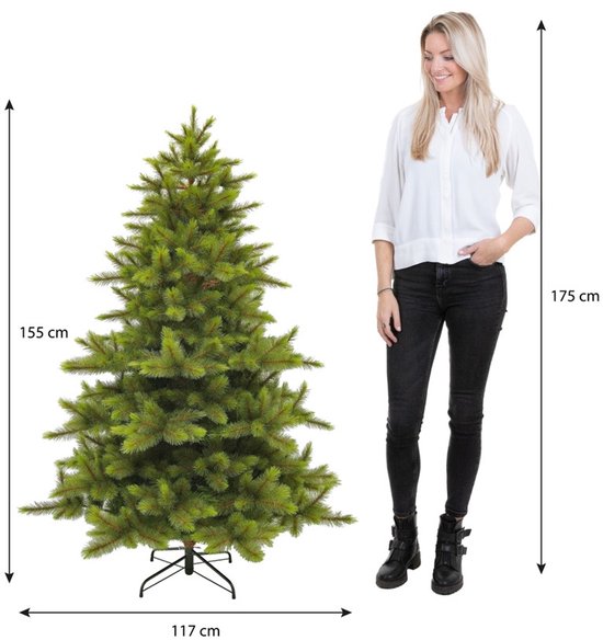 Vrouw naast een 155 cm hoge Triumph Tree kunstkerstboom, met afmetingen van 155 cm en 117 cm.