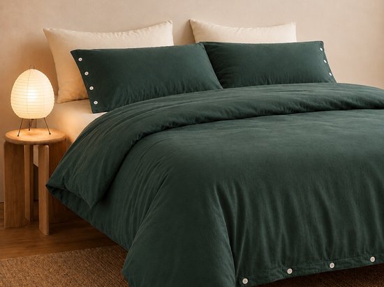 Donkergroen bed met dekbedovertrek en kussenslopen met knoopsluiting.
