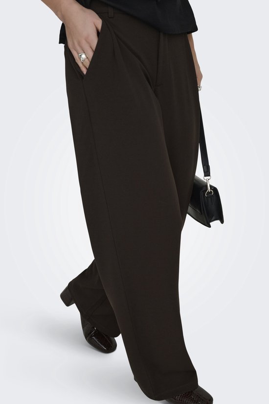Model loopt in donkerbruine wijde broek met croco schoenen en zwarte tas.