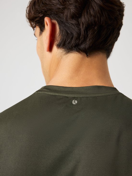 Achterkant van de nek van een man in een donkergroen sportshirt met een klein grijs logo op de nek.
