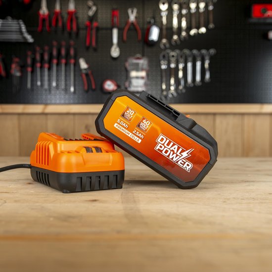 Oranje en zwarte Dual Power batterij en oplader op een houten tafel.