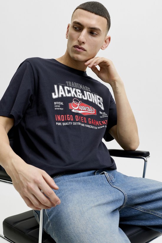 Man zit op stoel in Jack & Jones T-shirt met logo en spijkerbroek.