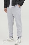 Man met lichtgrijze joggingbroek, wit T-shirt, zwart jasje en witte sneakers.