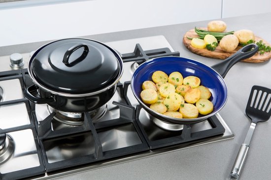 Zwarte braadpan naast een pan met gebakken aardappelen op gasfornuis.