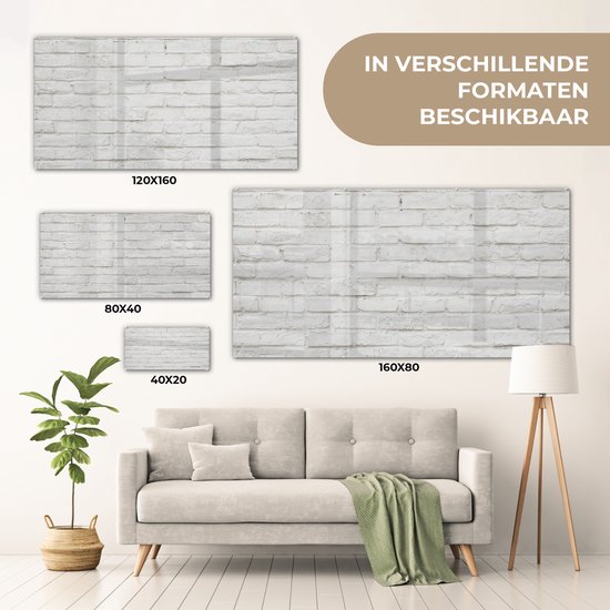 Groot acrylglas schilderij met witte baksteen textuur, getoond in een woonkamer op een bank. Verkrijgbaar in 120x160, 80x40 en 160x80 cm.