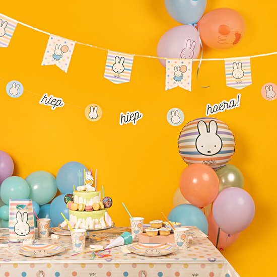Guirlandes colorées à l'effigie de Miffy, ballons festifs, gâteau et décoration de table.