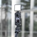 Insta360 X3 camera in een zwarte Ulanzi kooi, met een klein vierkant wit videolampje erbovenop, gemonteerd op een statief.