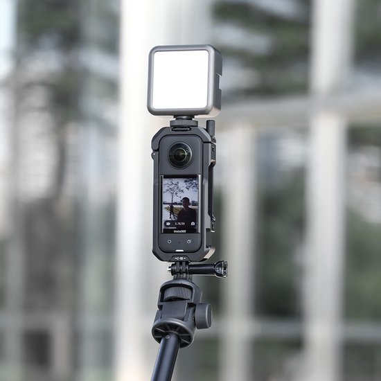 Insta360 X3 camera in een zwarte Ulanzi kooi, met een klein vierkant wit videolampje erbovenop, gemonteerd op een statief.