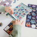Mains déchirant une feuille d'autocollants bleu clair avec des images de Stitch et le texte 'STAY COOL'.