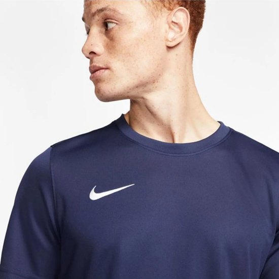 Close-up van een donkerblauw Nike sportshirt met witte Nike swoosh.