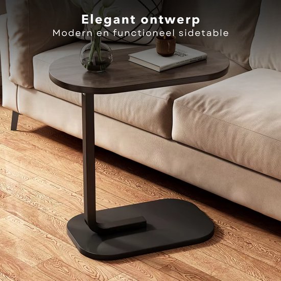 Zwarte bijzettafel met ovaal houten blad naast een beige bank.