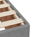 Détail du revêtement en tissu gris clair d'un sommier avec lattes en bois.