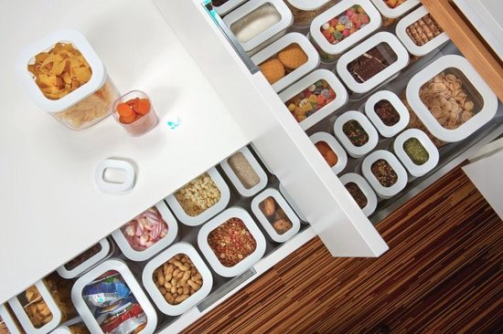 Contenants de stockage Mepal Modula remplis de pâtes, bonbons et épices sur un plan de travail blanc.