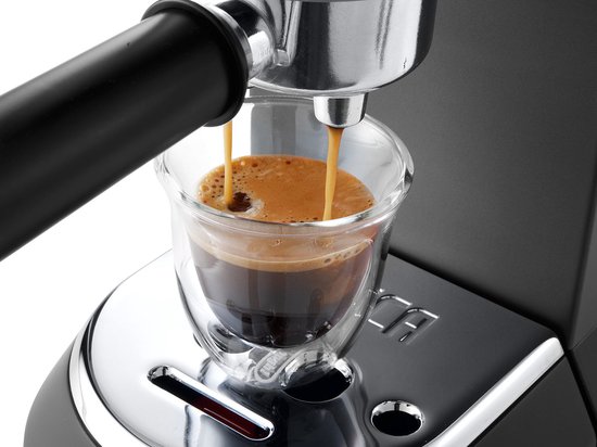 Espresso wordt uitgestroomd in een dubbelwandig glas uit een zwarte De'Longhi pistonmachine.