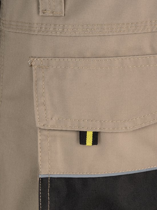 Salopette de jardin beige avec poche plaquée, accent noir et réfléchissant en bas.