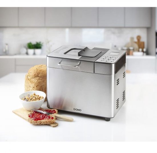 RVS broodbakmachine met een vers gebakken brood, kom muesli en toast met jam.