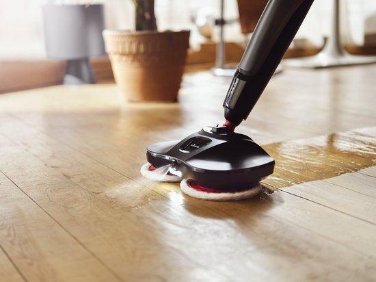Zwarte Vileda Looper vloermop met roterende witte en rode pads maakt een houten vloer schoon.