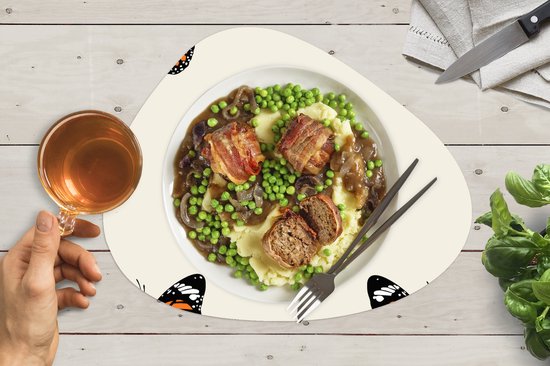 Crèmekleurige placemat met oranje vlinderprint, met een bord met gehaktbrood en aardappelpuree en een glas thee.