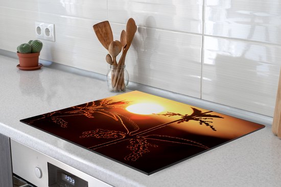Een snijplank met een brandnetel in silhouet tegen een oranje zonsondergang, op een kookplaat.