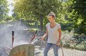 Een jonge vrouw gebruikt een GARDENA Comfort EcoPulse spuitpistool om een kruiwagen te besproeien.
