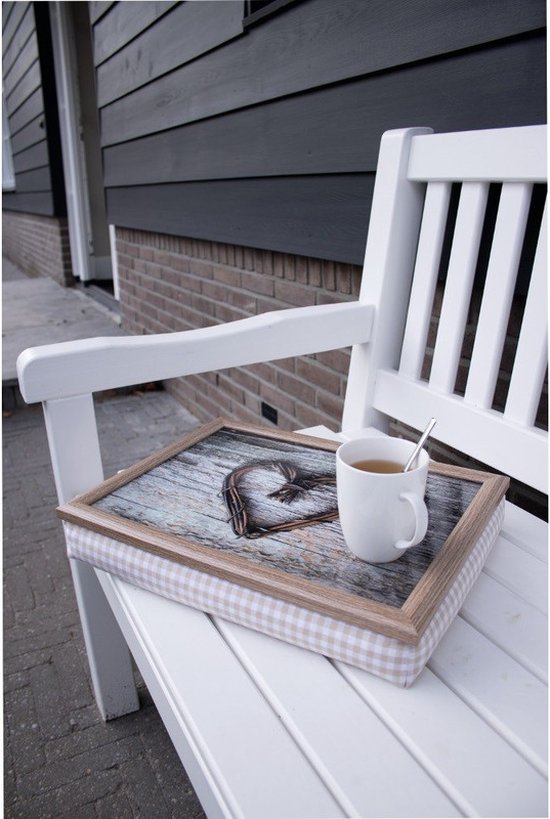 Schootkussen met een houten dienblad met een gevlochten hartje van takjes, staand op een witte tuinbank naast een mok thee.