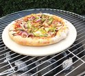 Pizza met paprika, ui, olijven en champignons op een pizzasteen boven houtskool.