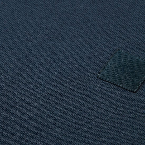 Detail van donkerblauwe stof met een ingeweven vierkant logo.