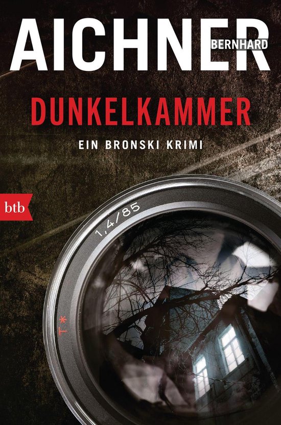 Boekomslag met de titel DUNKELKAMMER. Een donkere lens reflecteert een oud, spookachtig huis met spinnenwebben.