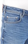 Blauwe jeans met een coin pocket, koperkleurige knopen en bruin leren label.