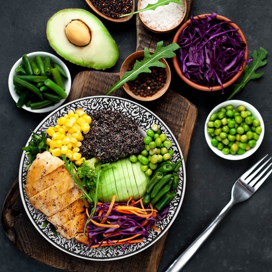 Gegrilde kipfilet met quinoa, avocado, maïs, groene bonen, rode kool en peterselie in een decoratieve kom.
