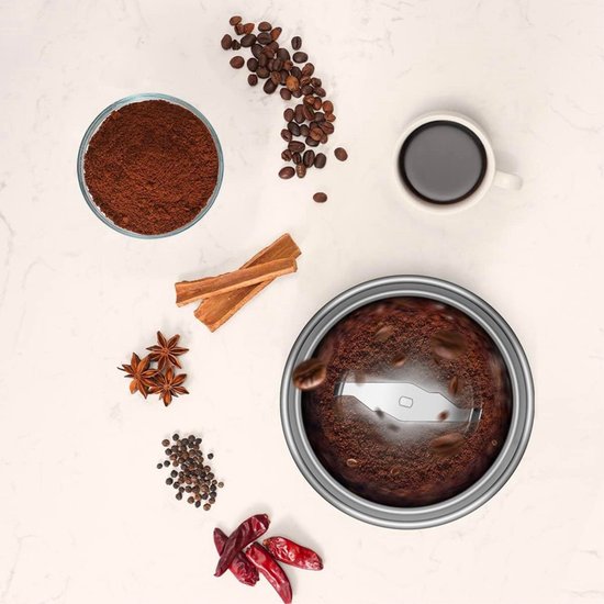 Malende koffiebonen in een Safecourt koffiemolen, omringd door specerijen en koffie.