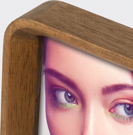Close-up van een houten fotolijst met een gezicht van een vrouw met groene oogschaduw.