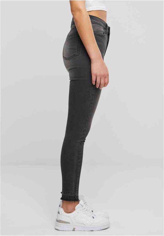 Zij-aanzicht van een dames skinny jeans in zwart gewassen denim met rafelige zoom.