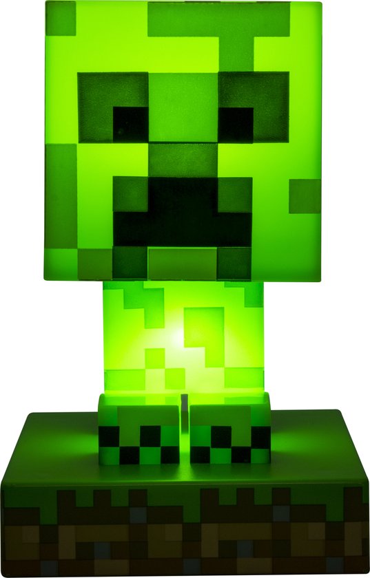 Een felgroene Minecraft Creeper-lamp, gloeiend met intern licht, staand op een gras- en aarde-voetstuk.