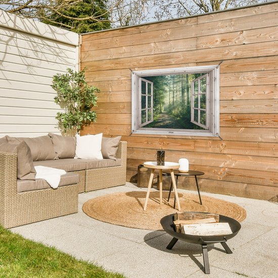 Tuinposter van een bos met zonnestralen, opgehangen aan een houten schutting boven een loungeset.