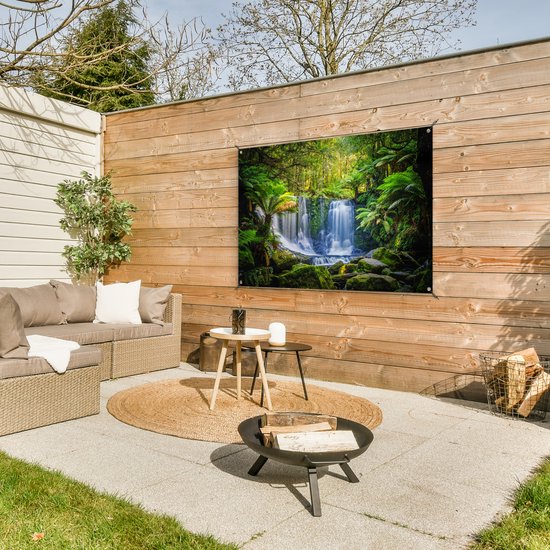 Waterval in een groen bos, met varens en mos, aan een houten schutting.