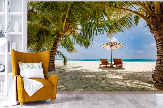Chaises longues entre les palmiers sur une plage de Bali fotobehang