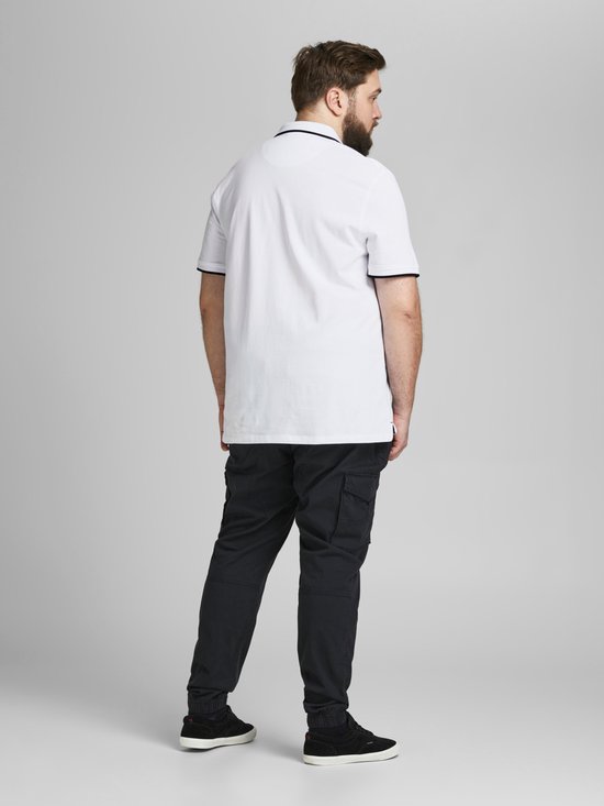 Man van achteren gezien in wit poloshirt met donkerblauwe randen, draagt donkere cargo broek.