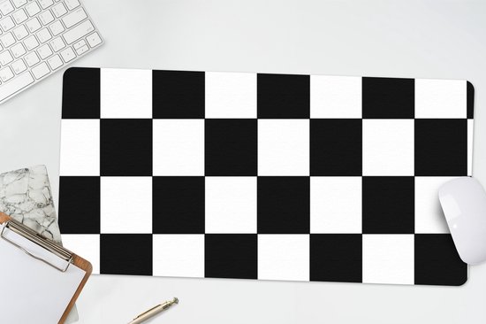 XL muismat met zwart-wit schaakbordpatroon, op een bureau naast een witte muis en toetsenbord.
