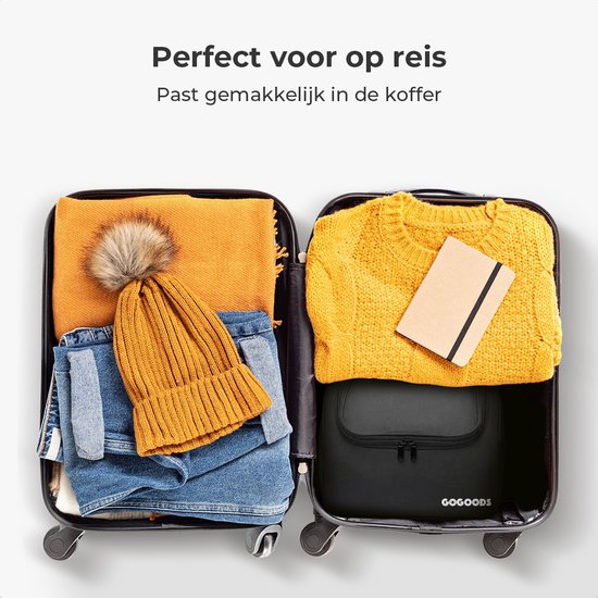 Zwarte GoGoods toilettas in een open koffer tussen kleding, naast een andere koffer met gele trui en notitieboekje.