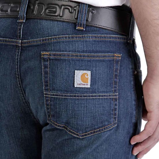 Achterkant van een spijkerbroek van donker denim met een Carhartt-logo.
