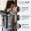 Vrouw draagt grijze ONYX rolrugzak, met details van gesp, waterdichte rits en 900D polyester.